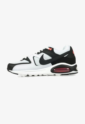 Sneaker atletico bianco e nero con tomaia in mesh, colletto imbottito e dettagli rossi. Presenta un cuscinetto d'aria nel tallone e suola in gomma.