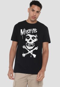 Black cotton t-shirt featuring a prominent white skull and crossbones graphic, with the word "Misfits" above in a distressed style.