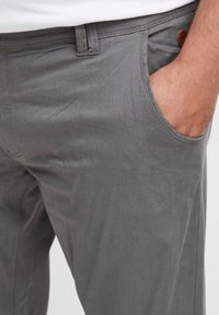 Graue Baumwollhosen mit slim fit, ausgestattet mit einem flachen Bund, Seitentaschen und einem Lederlogo-Akzent am Bund.