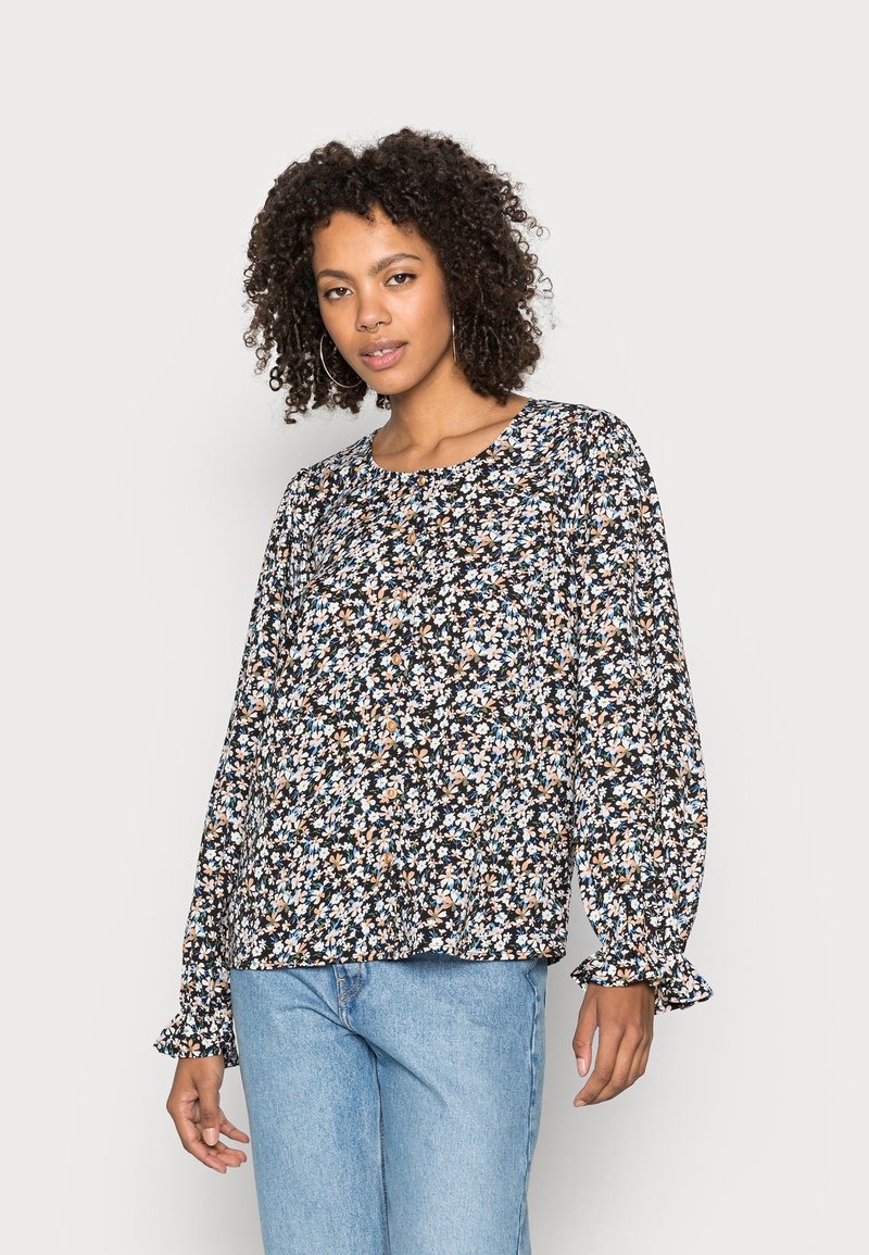 Blusa floral com mangas bufantes longas, decote redondo, fundo preto e padrões de flores multicoloridas. Tecido texturizado com punhos franzidos.
