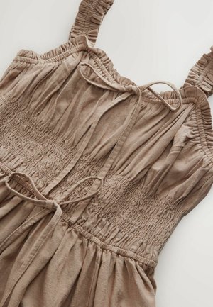 Ruskea ilman hihoja oleva mekko, jossa on ryppyilevä yläosa, säädettävät näkymättömät olkaimet ja hupullinen hameosa. Valmistettu pehmeästä ja teksturoidusta kankaasta, joka on rento malli.