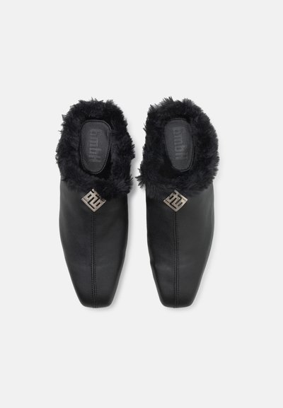 Chaussures slip-on en cuir noir avec un col en fourrure noire et un accent en logo argenté. Présente un design lisse et arrondi avec des détails cousus.