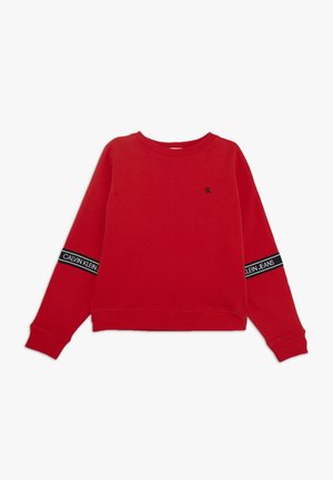 Sudadera roja de manga larga con pequeño logo negro "cK" en el pecho y bandas negras con texto "Calvin Klein Jeans" en ambas mangas.