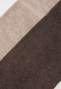 Strickstoff in drei horizontalen Abschnitten: hellbeige, taupe und dunkelbraun. Weiche Textur mit subtilen Variationen in den Farbtönen.
