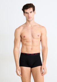 Schwarze Boxer-Briefs mit einem roten "HUGO"-Logo-Bund. Weiches Baumwollmaterial, körpernahe Passform und mittelhoher Schnitt für Komfort und Unterstützung.
