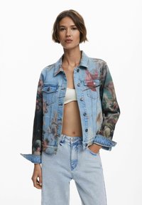 Veste en denim avec un tissu bleu et un imprimé floral sur les manches. Fermeture à boutons, deux poches poitrine et col classique. Jean délavé.