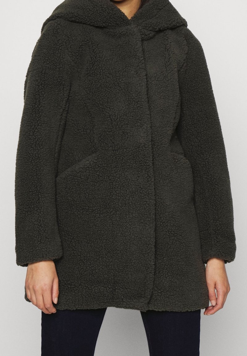 Abrigo de forro polar texturizado en gris oscuro, con capucha, bolsillos frontales y corte recto. Material suave y esponjoso con detalles de costura sutiles.