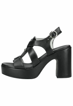 Sandalia de plataforma de cuero negro con tacón grueso, punta abierta, múltiples tiras y hebilla ajustable en el tobillo.