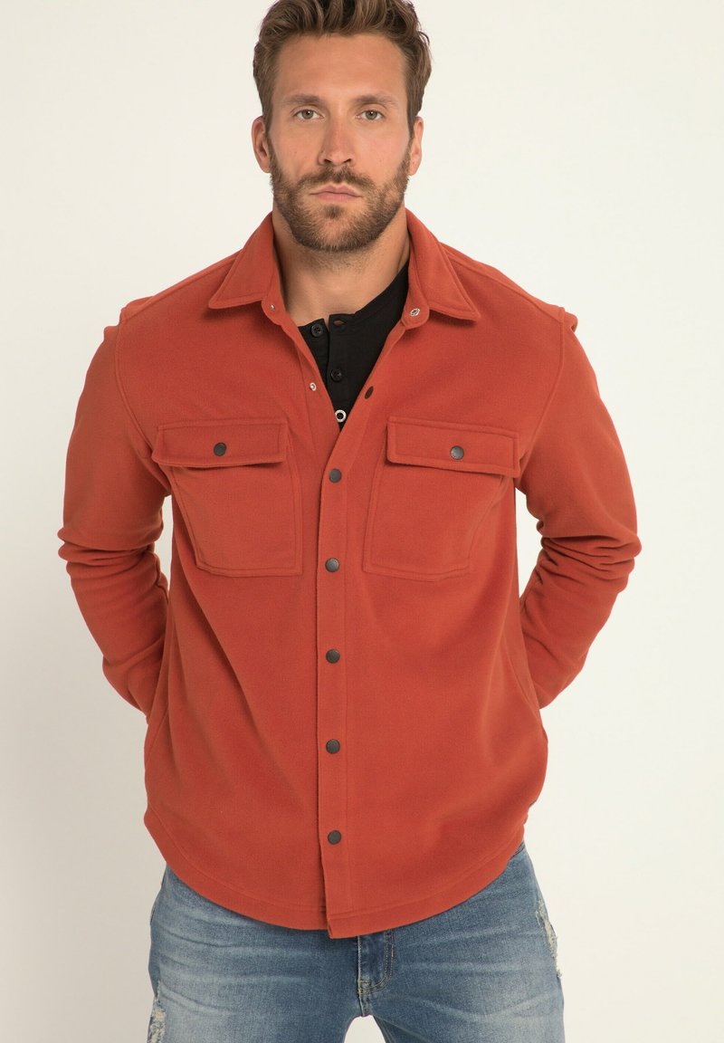 Rote Fleece-Jacke mit Knopfverschluss, zwei Brusttaschen, schwarzen Druckknöpfen und einem Hemdkragen. Weicher Stoff und lässige Passform.