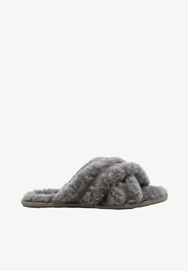 Chaussons gris en peluche avec un extérieur doux et moelleux, présentant un design en croix et une semelle plate. Le matériau semble duveteux et confortable.