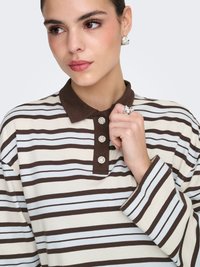 Polo à manches longues rayé en crème et marron, avec un col marron et trois boutons en strass au niveau du cou. Tissu en coton doux.