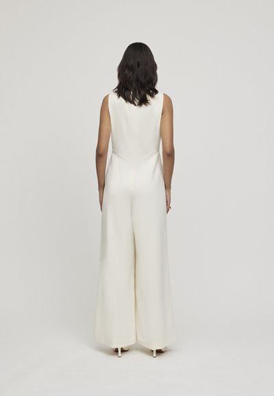 Ivory jumpsuit met een aansluitend lijfje en een wijde broekspijpen ontwerp. Glad stof, zonder mouwen, met een ritssluiting op de rug en een strakke silhouet.