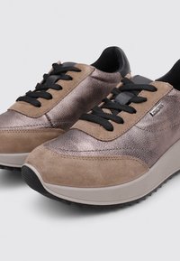 Zapatillas con parte superior de cuero metálico bronce y gamuza marrón claro, cordones negros y una suela de goma texturizada para agarre y soporte.