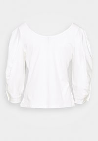 Vit bomullstopp med off-the-shoulder skall, puffärmar och figurnära midja. Mjuk textur, inga synliga mönster eller metall detaljer.