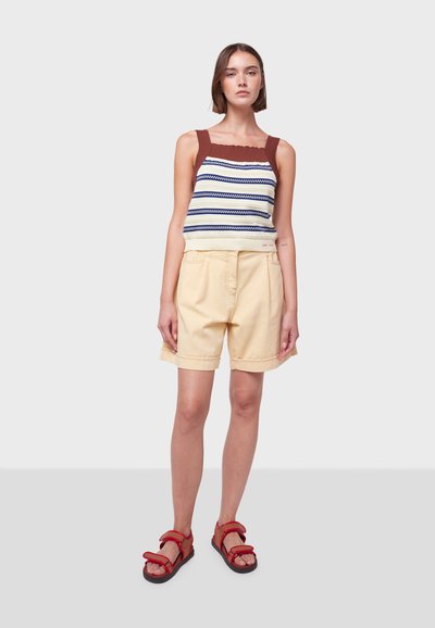 Débardeur en tricot rayé avec des bretelles marron, associé à un short jaune pâle et des sandales rouges. Design décontracté avec des d�étails texturés.