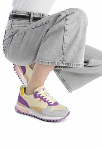 Sneaker multicolore con una tomaia crema, accenti viola e gialli, un puntale testurizzato e una suola imbottita con una striscia rosa.