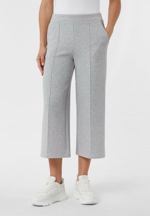 Pantaloni grigi a bermuda realizzati in tessuto morbido con tasche laterali, caratterizzati da un taglio dritto, cuciture accentuate, abbinati a sneakers bianche.