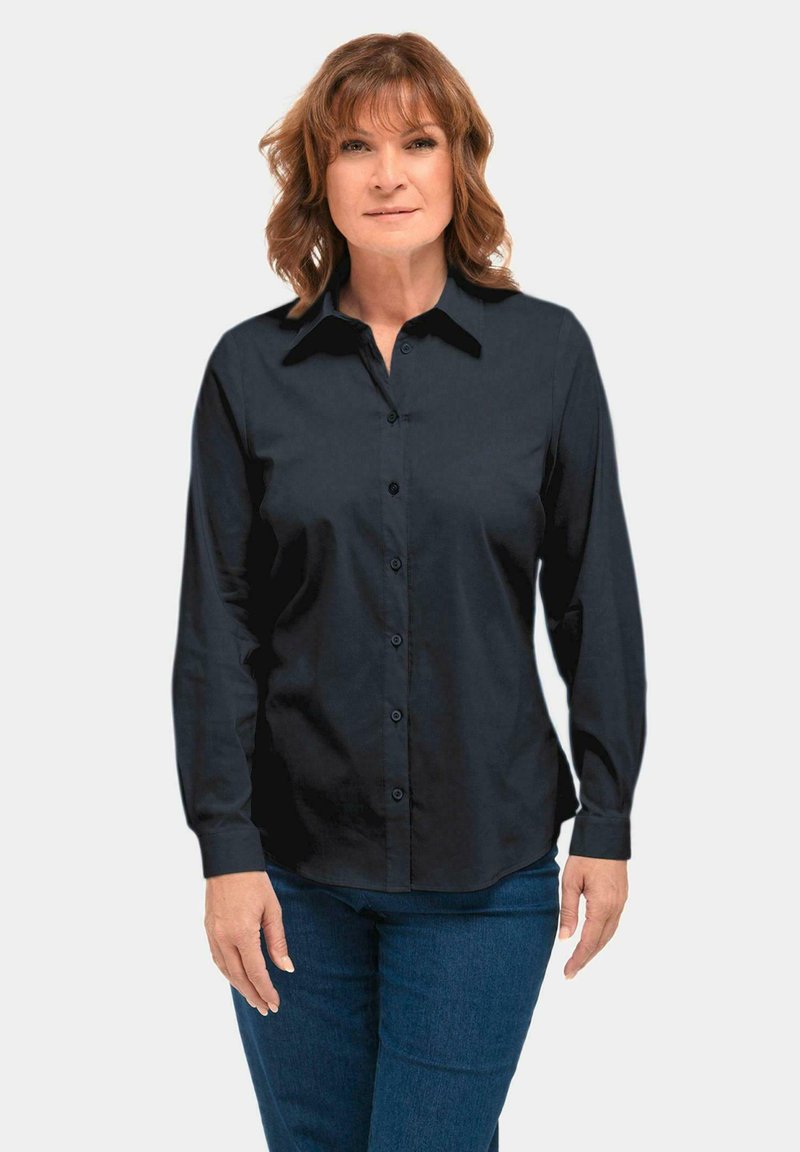 Black button-up shirt with a collar, long sleeves, and a smooth texture. Worn over blue denim jeans. Simple, classic design.