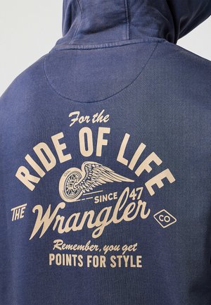Mörkblå hoodie med en stor krämfärgad grafik på baksidan som visar text och en motorcykel med vingar, texturerat tyg, avslappnad passform.