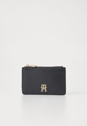 Black leather wallet with a textured finish, featuring a gold logo at the front and a zip closure at the top.