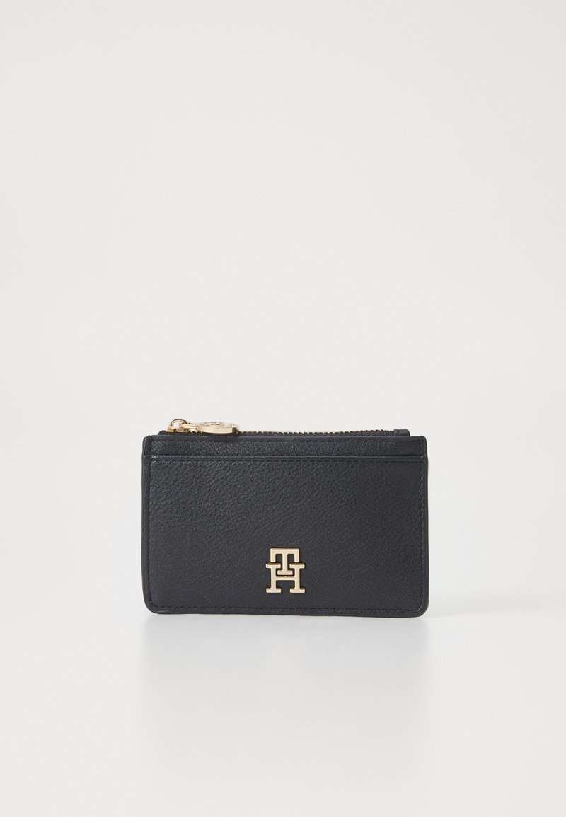 Black leather wallet with a textured finish, featuring a gold logo at the front and a zip closure at the top.