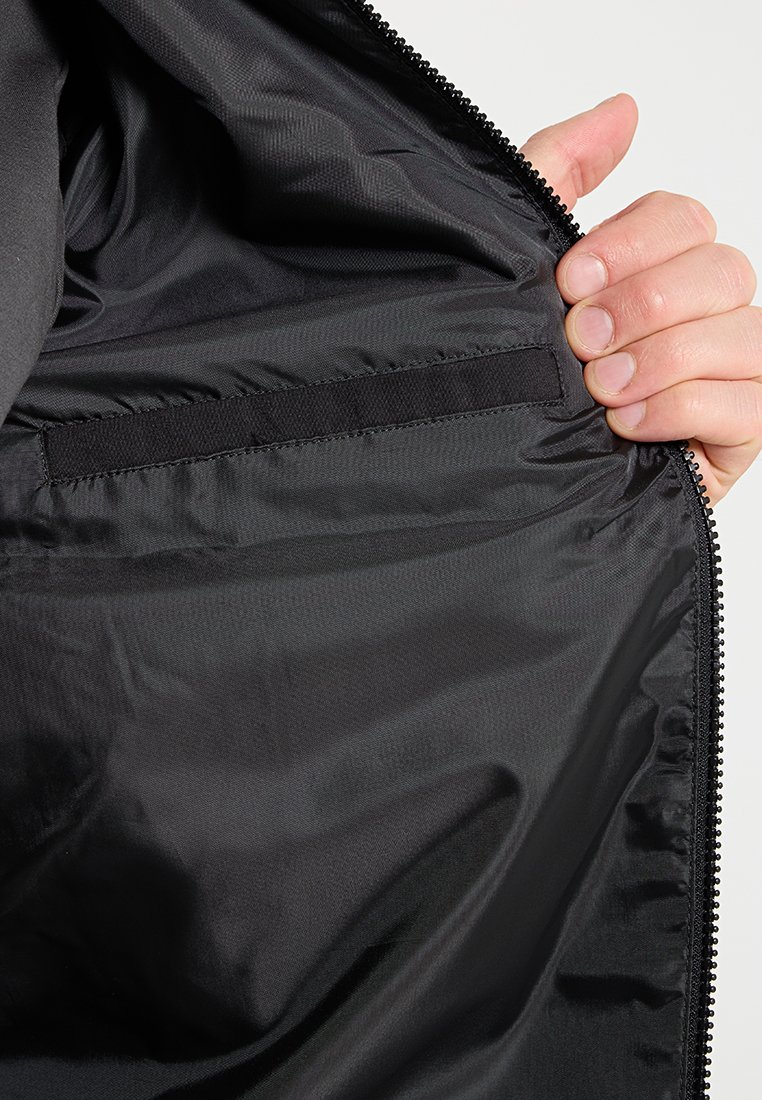 Doublure intérieure noire d'une veste avec une texture lisse, fermeture éclair et une petite poche cousue dans le tissu.