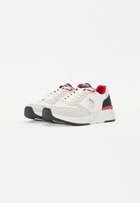 Sneaker bianche con tomaia in suede e mesh, dettagli rossi sul tallone e sulla linguetta, suola grigia, collo imbottito e suola in gomma nera.