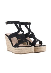Sandalias de cuña trenzadas negras con cintas entrecruzadas, plataforma y tacón de yute tejido, que presentan una elegante tira en el tobillo y un detalle dorado.
