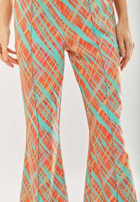 Colorful flared pants feature an orange, turquoise, and pink plaid pattern with diagonal stripes and a smooth fabric texture.
