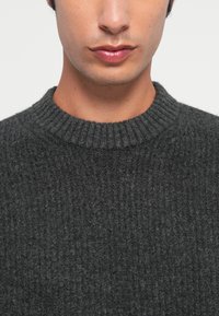 Gray knitted sweater with a ribbed texture and a round neckline, showcasing a soft, thick material and a close-fitting design.