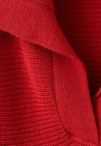 Tela de punto roja con un patrón texturizado acanalado, que presenta un cuello doblado. El material parece suave y cálido, con un tono rico y profundo.