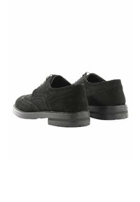 Scarpe in suede nero con dettagli brogue, punta tondeggiante e suole in gomma piane, dotate di un design con lacci e accenti di cucitura a contrasto.