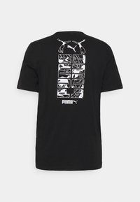 Černé tričko Puma s bílým grafickým textem a logem Puma na zadní straně, obsahující dvě akrobatické postavy a abstraktní vzory.