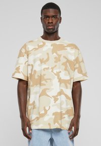 Kortærmet t-shirt i beige med camouflage mønster; lavet af blødt stof med en afslappet pasform og rund halsudskæring.