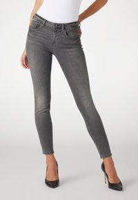Anpassade grå denimjeans med en klassisk femficksdesign, subtil blekning, uppvikt fåll och en mjuk textur, kombinerade med svarta högklackade skor.
