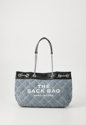 Bolso tote de denim acolchado con parte superior de cuero negro y acentos de cadena plateada. Presenta texto impreso en blanco: "THE SACK BAG MARC JACOBS."