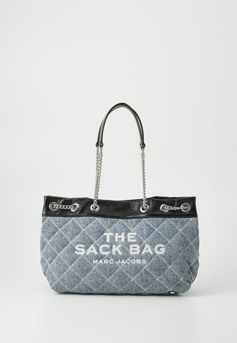 Pūšana džinsu soma ar melnu ādas augšdaļu un sudraba ķēdes akcentiem. Ar baltu drukātu tekstu: "THE SACK BAG MARC JACOBS."