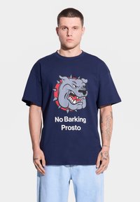 Granatowa bawełniana koszulka z grafiką szarego pit bulla z kolcami, z towarzyszącym mocnym białym napisem: "No Barking Prosto."