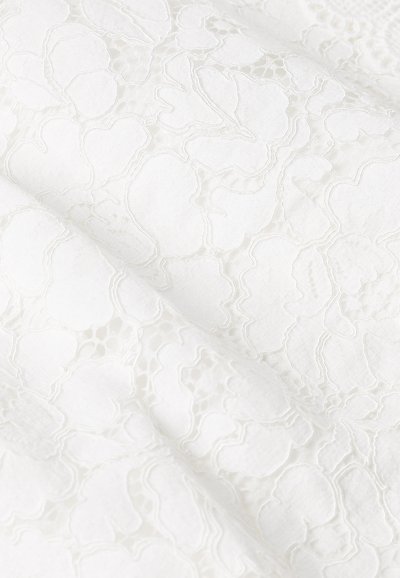 Tessuto in pizzo bianco con un motivo floreale, caratterizzato da una superficie testurizzata e dettagli in filo delicati. Aspetto morbido e leggero.