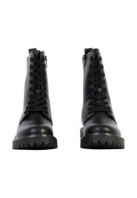 Paire de bottines en cuir noir à lacets avec semelles en caoutchouc épaisses, photographiées de face sur un fond blanc.