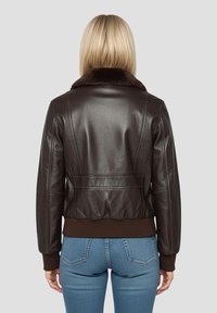 Donkerbruine leren jas met een bruine nepbontkraag, geribbelde manchetten en tailleband. Heeft gestructureerde naden en een cropped silhouet.