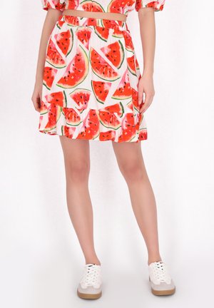 Witte rok met een levendig watermeloenprint, voorzien van een elastische tailleband en een gerimpelde zoom. Gepaard met witte sneakers.