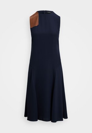 Vestido azul-marinho sem mangas com um destaque em couro castanho no ombro, design de saia evasé e um decote alto. Textura de tecido suave em todo o vestido.