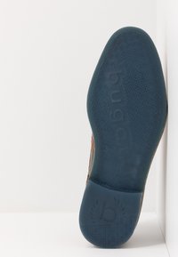 Semelle de chaussure en caoutchouc bleu texturé, avec le logo "bugatti" et une surface antidérapante motifée. Le côté présente un mélange de cuir marron et de matériau en maille.