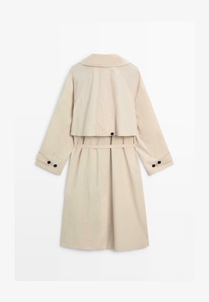 Trench beige con cintura, maniche lunghe, dettaglio del giogo posteriore e bottoni neri su polsini e spacco posteriore.