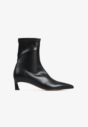 Czarne skórzane botki za kostkę z wydłużonym noskiem, niskim blokowym obcasem i dopasowaną cholewką. Gładka tekstura o minimalistycznym designie i bez widocznych elementów metalowych.