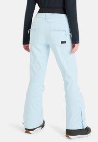 Jasnoniebieskie spodnie narciarskie o rozszerzanym kroju, z kieszeniami na zamek z tyłu i małą naszywką z logo. Wykonane z trwałego, teksturowanego materiału.