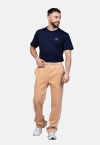 Marineblauwe katoenen T-shirt met een klein logo, gecombineerd met lichtbeige corduroy broek met een gestructureerde oppervlakte en witte zijkanten.