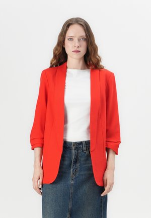 Rød skræddersyet blazer med lange ærmer, letvægtsstof, klapkrave og opsmøgte ærmer, parret med en hvid bluse og et denimskirt.