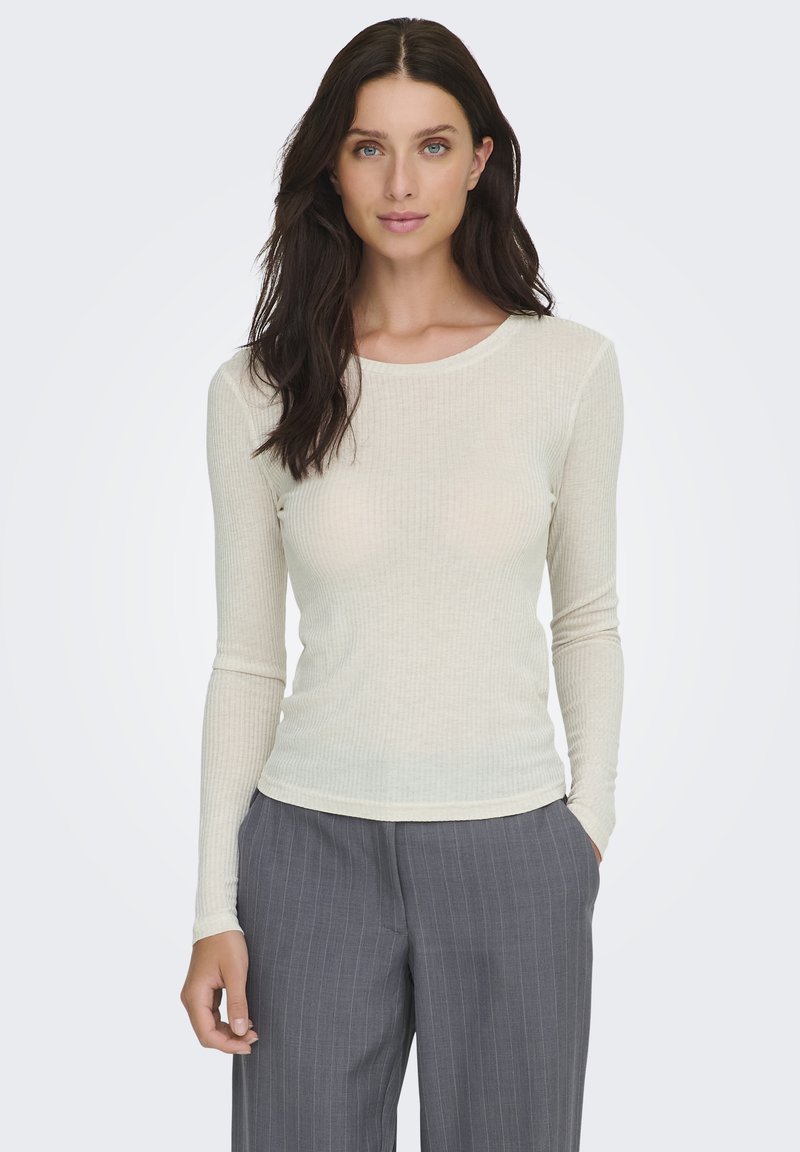 Top de manga larga y canalé en color crema claro, con escote redondeado y textura suave, combinado con pantalones grises de rayas finas.